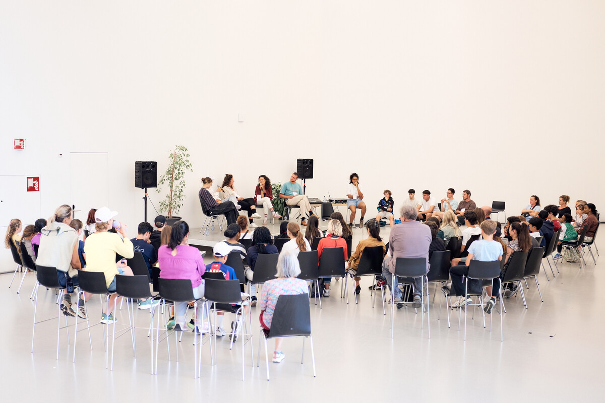 A large open circle of children, young people and adults in the hall of the Davos Congress Centre