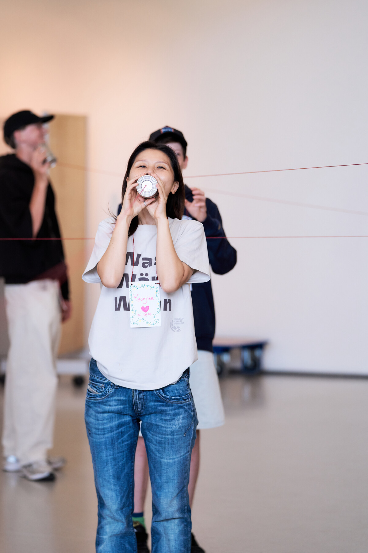 A girl listens through a tin-can telephone during a workshop